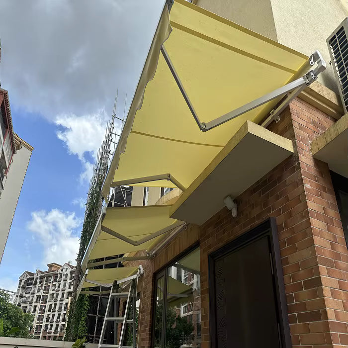 Toldo proyectante amarillo extendido sobre ventanal en fachada de ladrillo