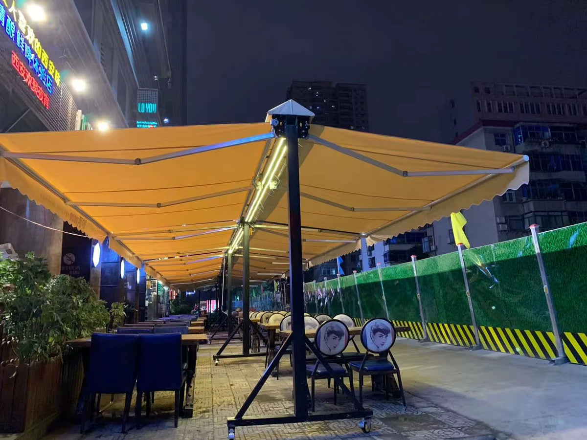 Toldos proyectantes dobles color amarillo con luces LED sobre terraza de restaurante de noche