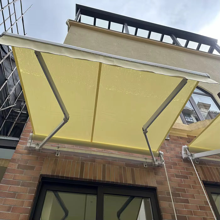 Vista inferior de toldo proyectante amarillo con brazos articulados instalado sobre una ventana