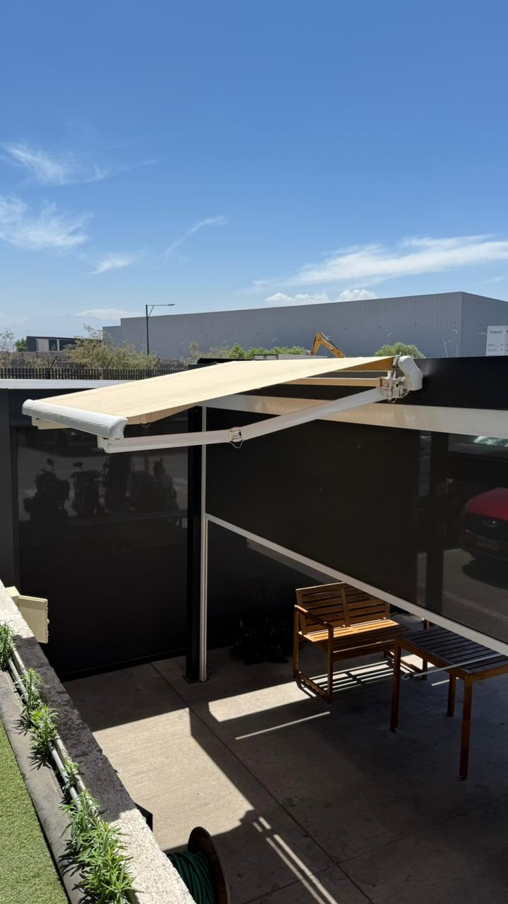 Instalacion real de toldo proyectante beige extendido en terraza exterior con muebles de madera