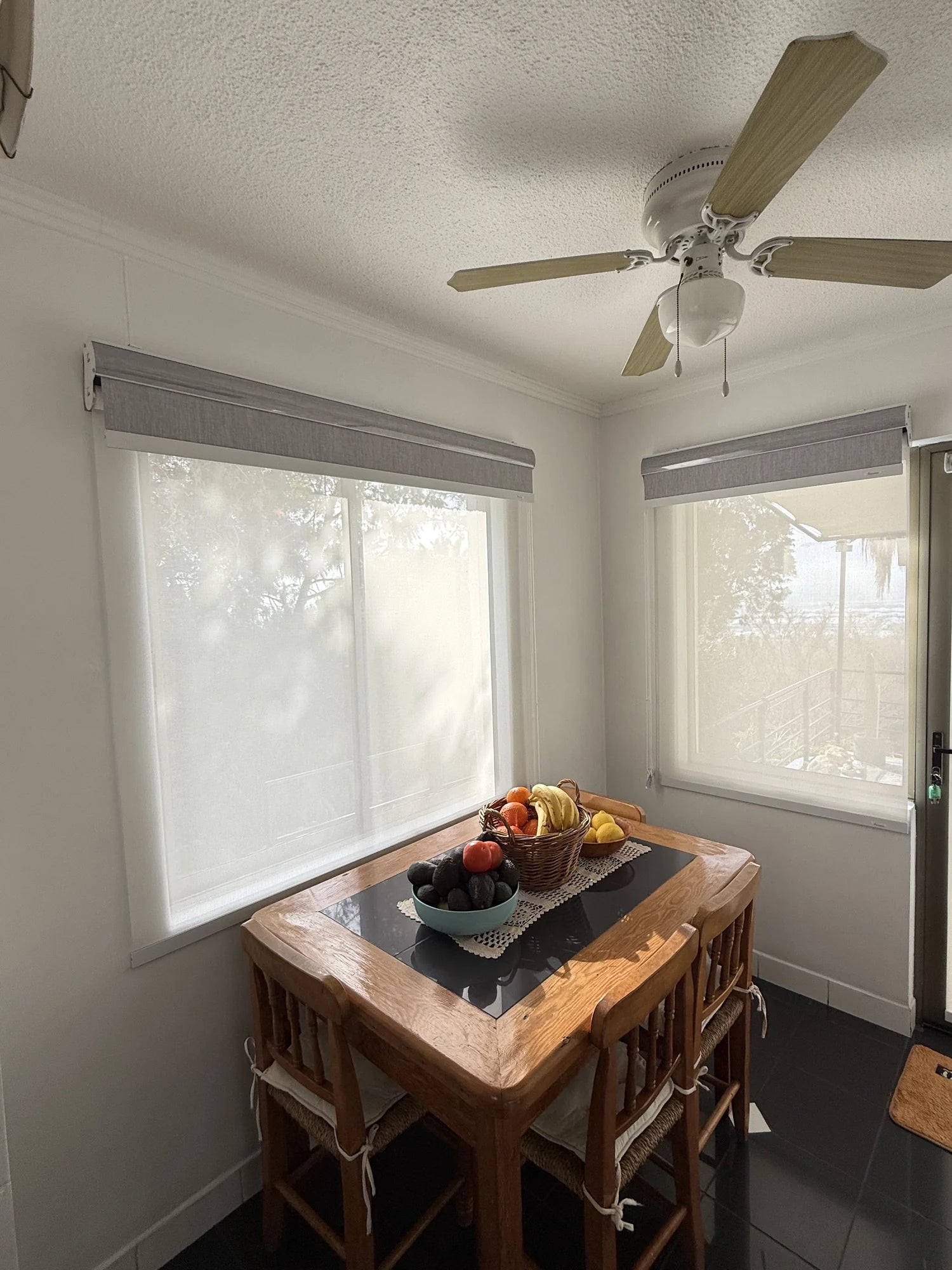 Cortinas roller dobles con tela sunscreen blanca instaladas en ventanas de comedor