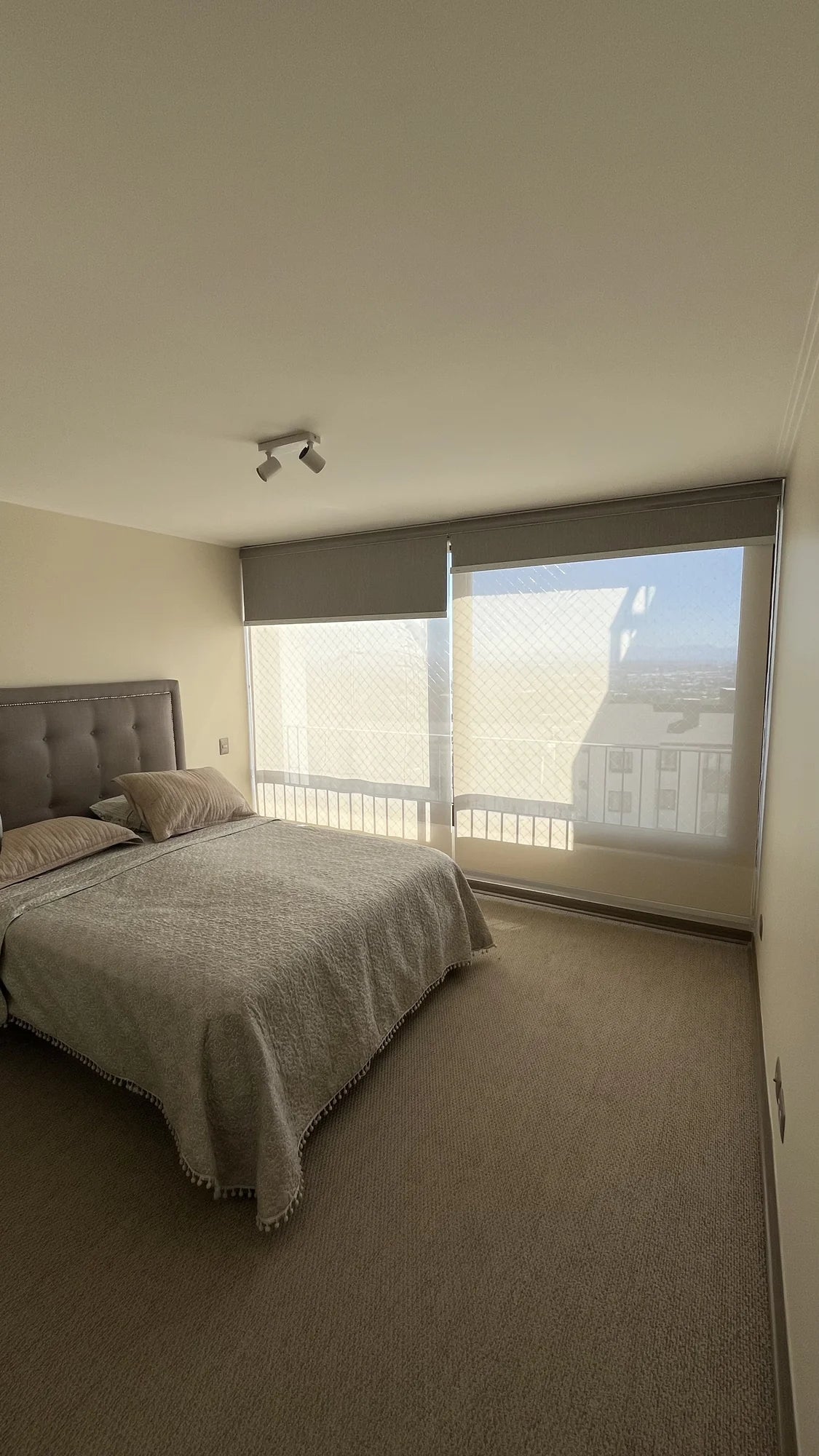 Cortina roller doble con blackout y sunscreen instalada en ventanal de dormitorio